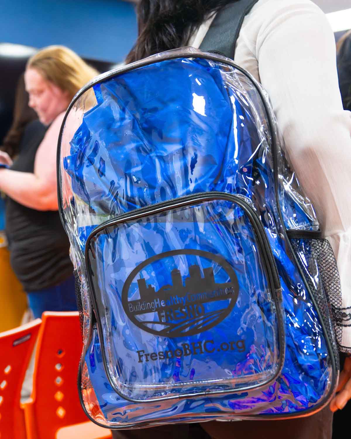 Close-up of a transparent blue backpack branded with the Building Healthy Communities Fresno logo, highlighting the supportive resources and tools provided through the Fresno BHC Youth Internships Program for aspiring youth leaders.