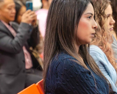 A young woman in a navy sweater attentively listening during the Fresno BHC Youth Internships Program session, reflecting focused engagement and commitment to community leadership.