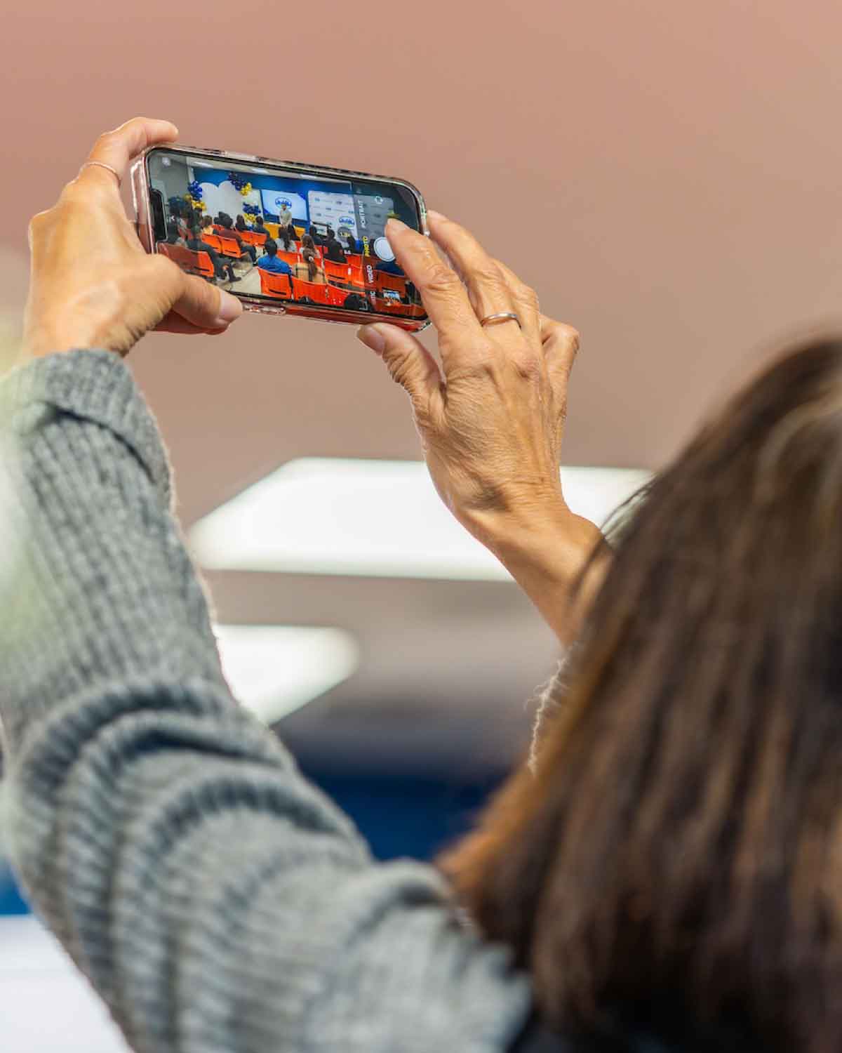 An attendee capturing the Fresno BHC Youth Internships Program event on a smartphone, reflecting the excitement and community engagement surrounding youth leadership opportunities.