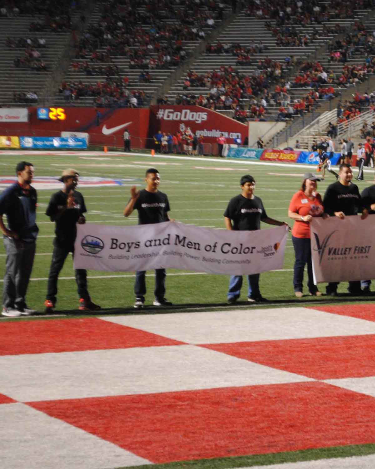 Members of the Boys and Men of Color group holding a banner on a football field, highlighting Fresno BHC’s commitment to youth empowerment, civic engagement, and encouraging more youth to join the internships program.