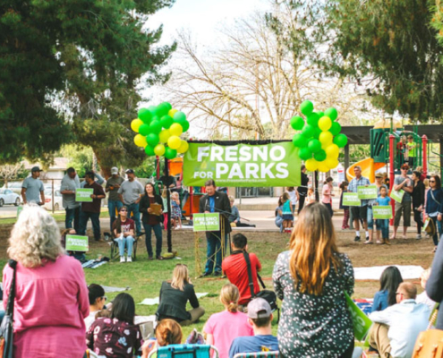 Community members gather at a Fresno park for a rally supporting the 'Fresno for Parks' initiative, advocating for increased park funding and access.