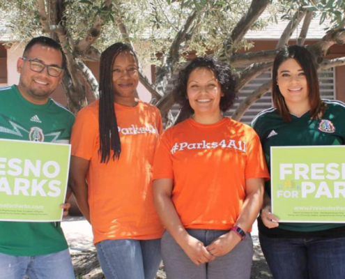 Sandra Celedon as well as Fresno BHC's staff and volunteers hold 'Fresno for Parks' signs and wear #Parks4All shirts, supporting equitable access to parks and green spaces.