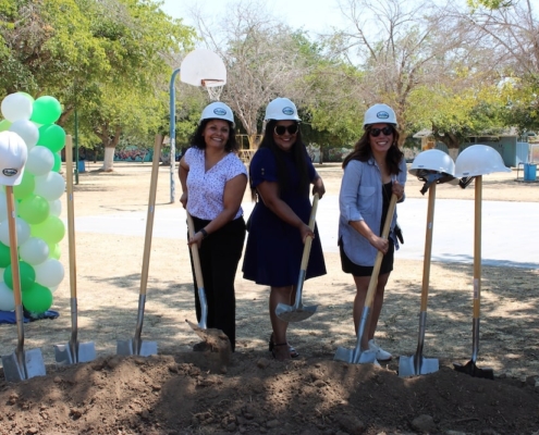 Three women leaders and park champions pose with shovels and hard hats at the Calwa Park groundbreaking site.