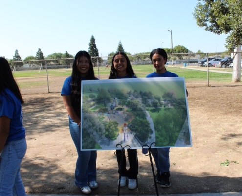 Youth volunteers proudly display a visual rendering of the future Calwa Park renovation project during the groundbreaking event.