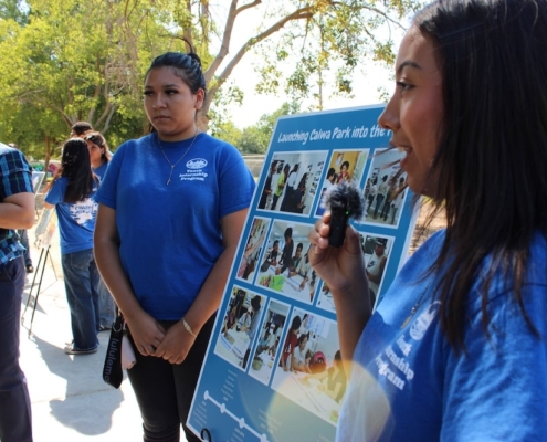 Youth leader shares insights into the community-led process behind Calwa Park's revitalization, standing beside a timeline display titled 'Launching Calwa Park into the Future.'