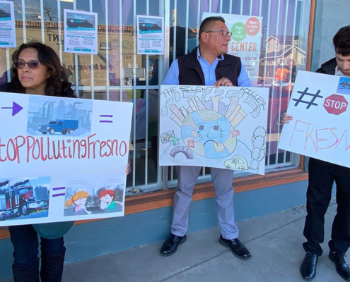 Community members in Fresno holding signs against freeway expansion and diesel truck pollution