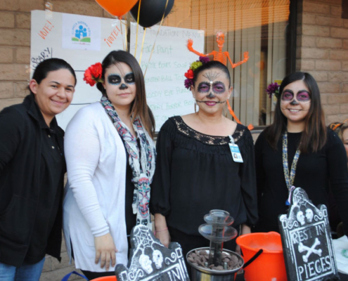 Fresno BHC volunteers dressed in Día de los Muertos face paint welcoming families at the Well-O-Ween community event