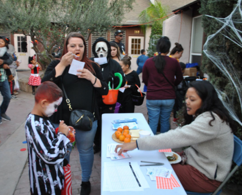 Families visiting the healthy snacks booth during Fresno BHC’s Well-O-Ween Halloween event