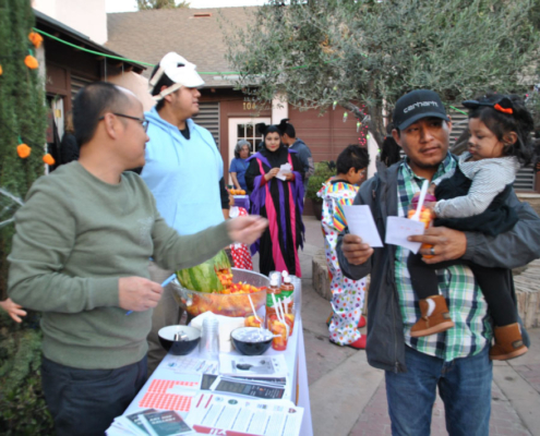 Fresno BHC volunteers sharing healthy snacks and flyers with families at the Well-O-Ween celebration