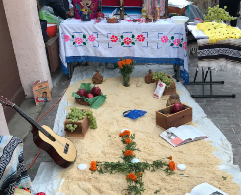 Close-up of Día de los Muertos altar display with marigolds, fruit, and guitar at Well-O-Ween Fresno