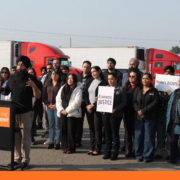 Community advocate speaks at a podium during a Fresno press conference calling for accountability after California DMV commercial license revocations.