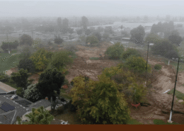 Aerial view of Calwa Park during renovation, showing a foggy construction site with earthwork underway and trees and nearby homes surrounding the area.