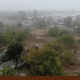 Aerial view of Calwa Park during renovation, showing a foggy construction site with earthwork underway and trees and nearby homes surrounding the area.