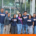 group of six smiling individuals standing outdoors in front of a glass-fronted building. They are wearing matching navy blue t-shirts that read "Better Roads. Safe Streets. Moving Forward Together." They are standing in front of a stack of several cardboard Banker boxes.